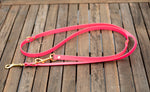 Pink and brass PVC leash on hardwood table